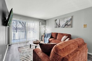 Un salon avec un canapé, une table basse et un téléviseur fixé au mur.