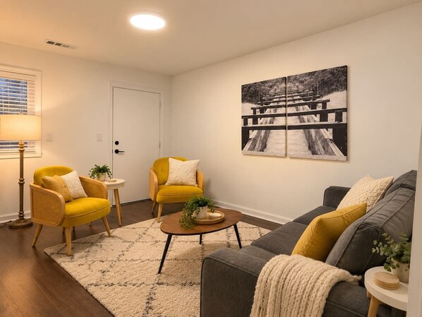 Ein Wohnzimmer mit einer Couch, zwei Sesseln, einem Couchtisch und einem Gemälde an der Wand.