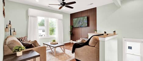 A modern living room with a sofa, coffee table, and a television mounted on the wall.
