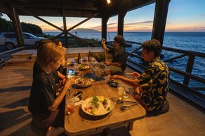 Puinen terassi, jossa on ruokapöytä katettuna, ja josta avautuu näkymä vesistölle.