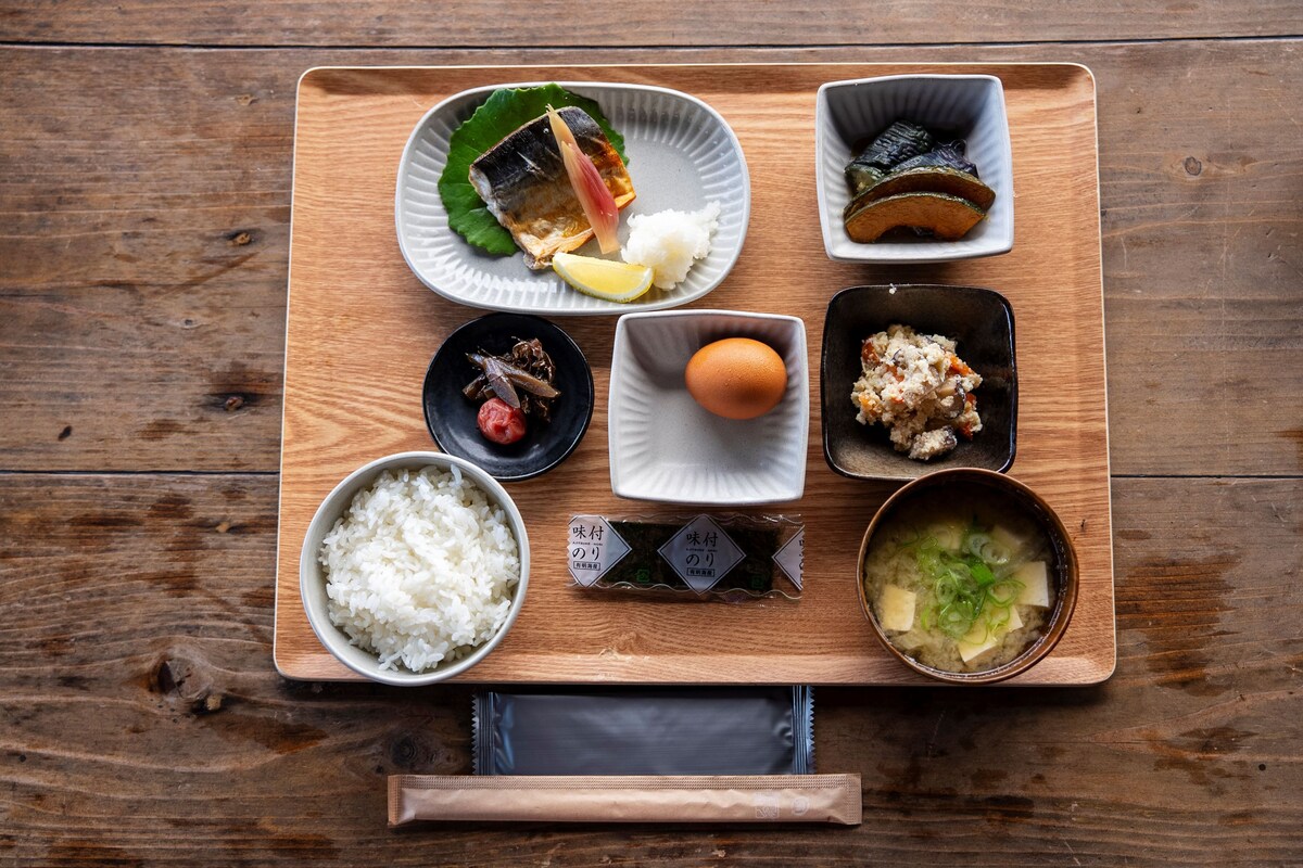 Puisesta tarjottimesta on katettu erilaisia japanilaisia ruokia, kuten riisiä, kalaa ja marinoituja kasviksia.