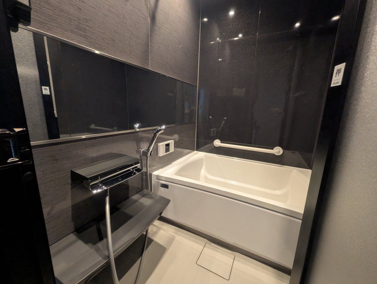 A modern bathroom with a bathtub, a vanity with a mirror, and a towel rack.