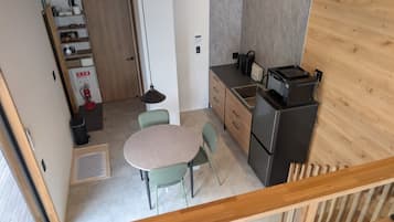 Una cocina compacta con comedor, un refrigerador y un armario de madera.