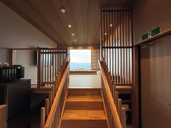 Un escalier en bois menant à un balcon d’où l’on peut admirer la vue sur les montagnes.