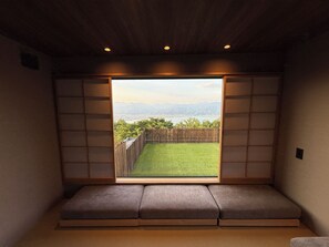 Une pièce donnant sur une pelouse verdoyante et une clôture en bois, avec un banc intégré le long de la fenêtre.