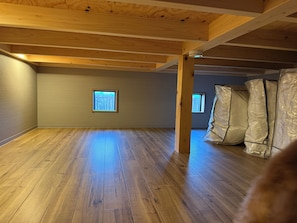 A room with wooden beams, a window, and a corner with insulation materials.