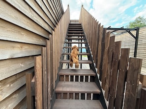 A wooden staircase leading to a deck area with a view of the sky.