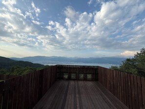 Une terrasse en bois offrant une vue sur un lac et des montagnes.