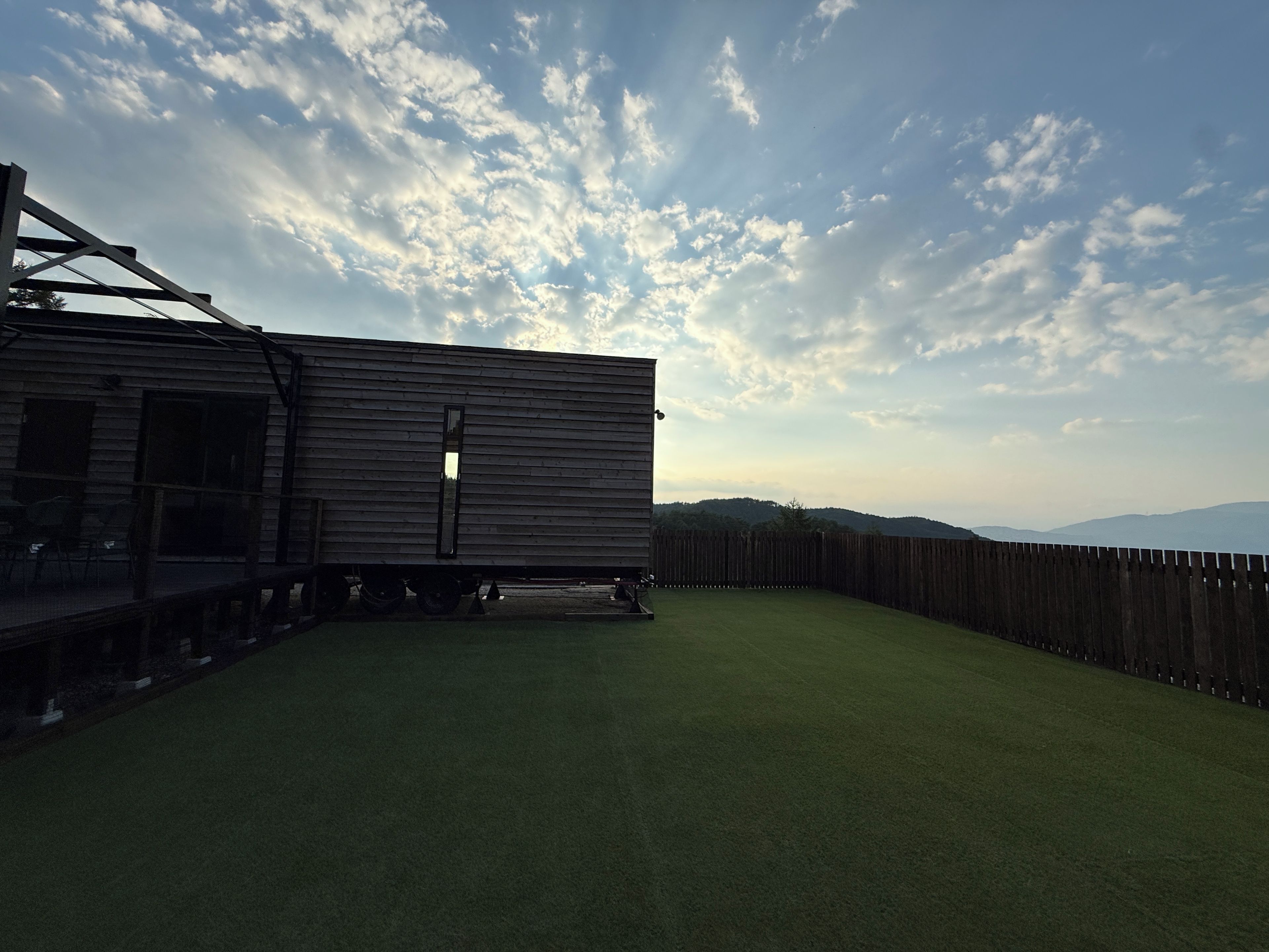 En trækonstruktion med terrasse og en indhegnet baghave.