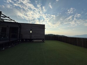 A wooden structure with a deck and a fenced backyard.