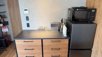 Une petite cuisine équipée d’un four à micro-ondes, d’un réfrigérateur et de meubles de rangement en bois.