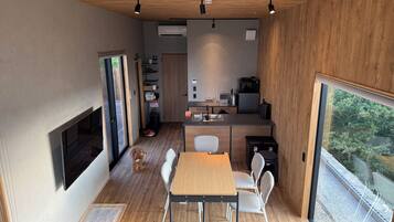 A modern kitchen with a dining area, wooden flooring, and a large window.