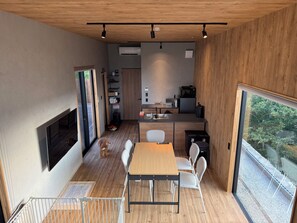 Une cuisine moderne avec un coin repas, un plancher en bois et une grande fenêtre.