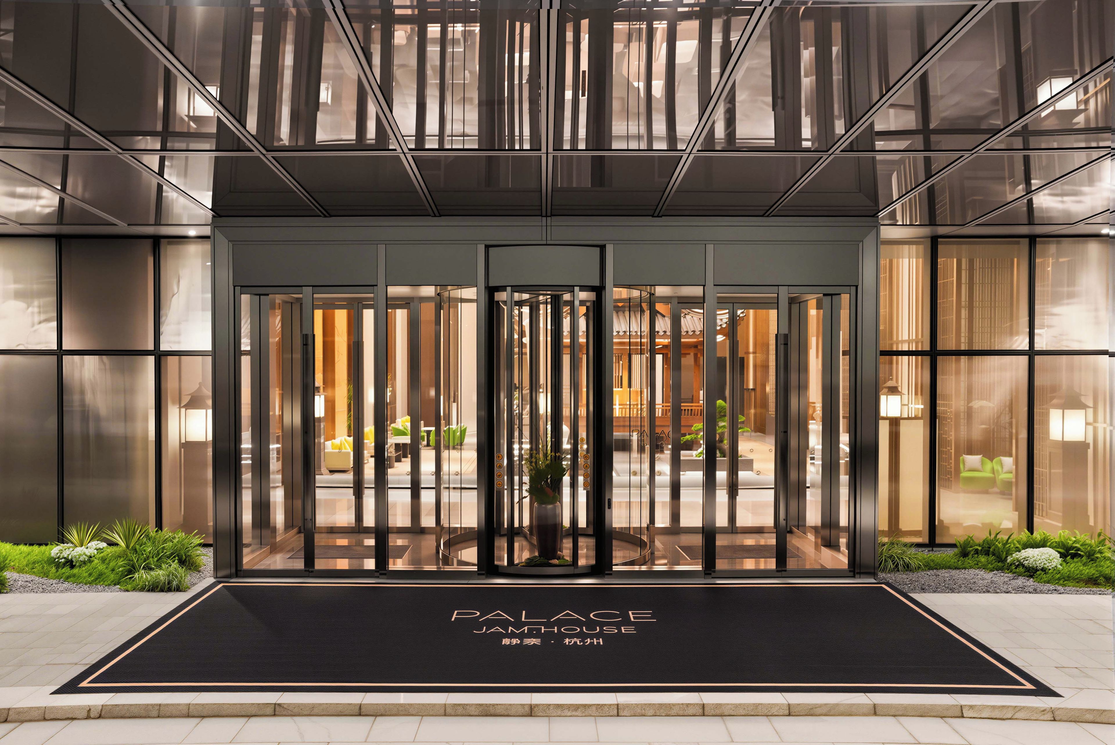 A modern building entrance with a glass door and a black mat with 'PALACE JAMHOUSE' signage.