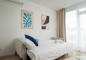 A hotel room with a bed, two pillows, a wall-mounted air conditioner, and two framed artworks. - Browary Warszawskie Essence Studio 390 (Warszawa)
