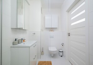 A modern bathroom with a toilet, sink, and mirror. - Browary Warszawskie Essence Studio 390 (Warszawa)