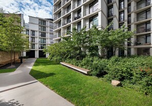 A modern apartment building with multiple balconies, a well-maintained lawn, and a pathway leading to the entrance. - Browary Warszawskie Essence Studio 390 (Warszawa)