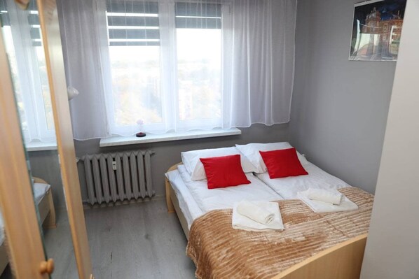 A bedroom with a bed, a window with curtains, a radiator, and a picture on the wall. - Głogów Comfort Stay Apartament (Głogów)