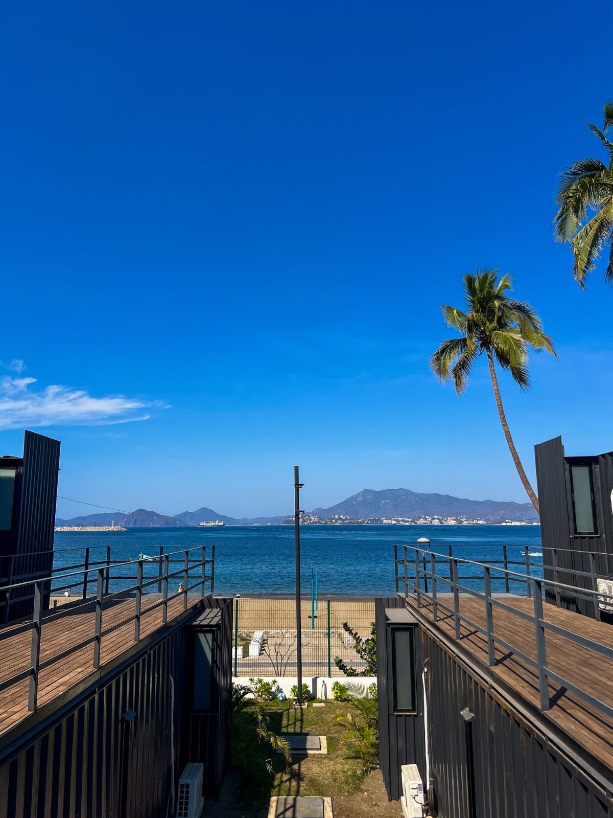 A wooden deck with a view of the ocean and mountains.