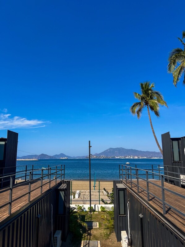 A wooden deck with a view of the ocean and mountains.