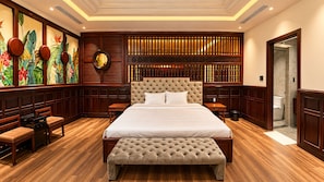 Ein geräumiges Schlafzimmer mit einem großen Bett, einer Bank, einem kleinen Tisch und einer Wanduhr.