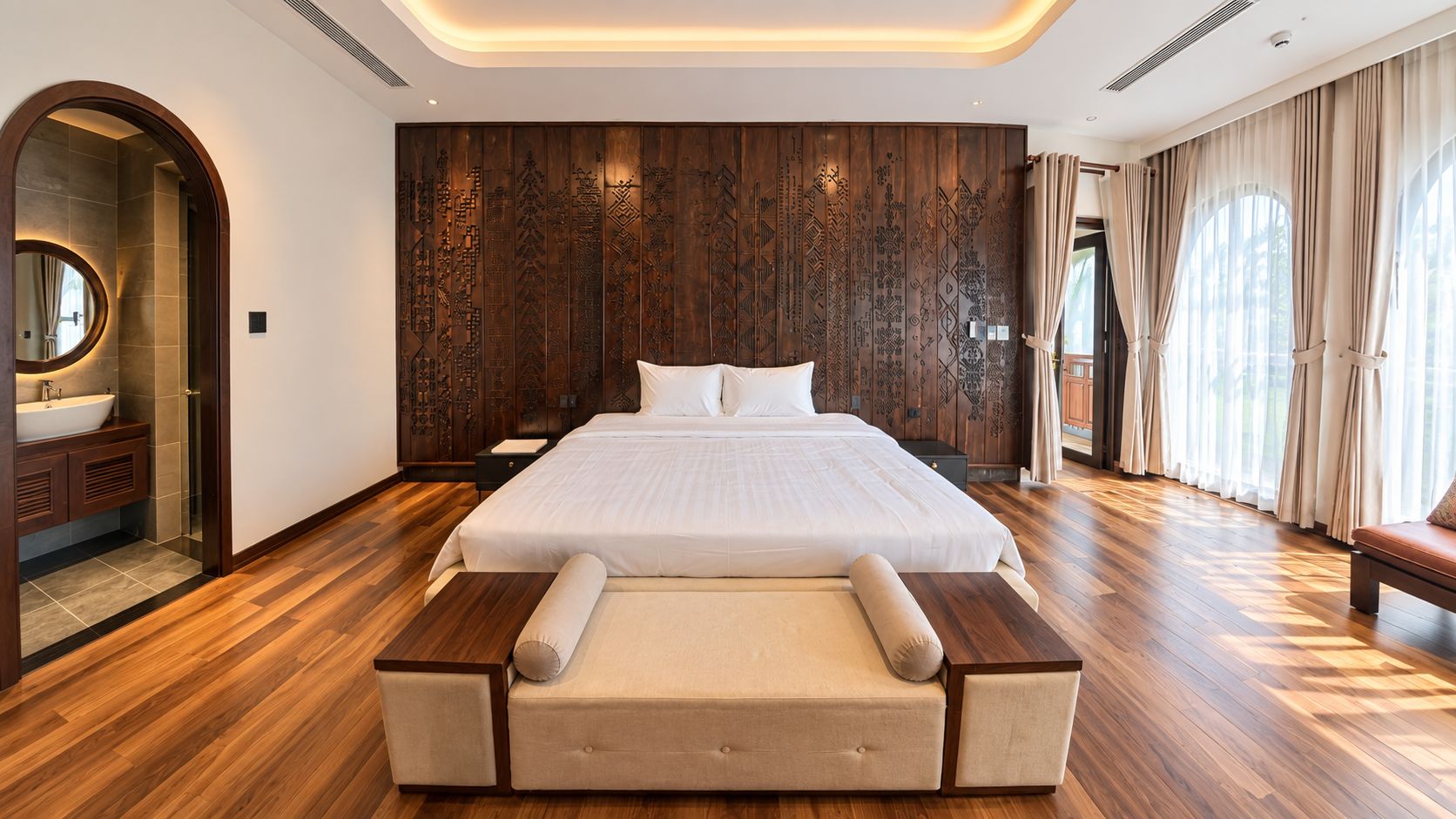 Um quarto espaçoso com uma cama grande, parede de painéis de madeira e vista para o exterior pela janela.