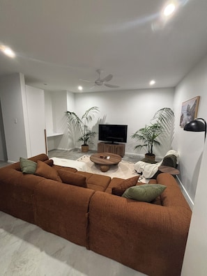 A modern living room with a brown sofa, a coffee table, and two potted plants.