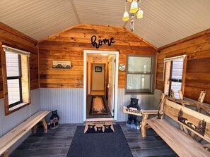 A wooden cabin interior with a 'home' sign, a bear-themed welcome mat, and a bench. - Hot Tub • Private Pond • 12-Acr Retreat • Sleep 14 (Binghamton)