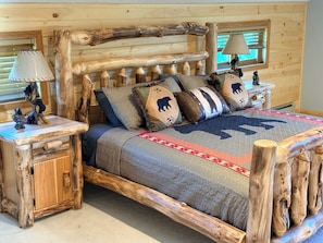 A wooden bed with a headboard, two nightstands, and a window with blinds. - Hot Tub • Private Pond • 12-Acr Retreat • Sleep 14 (Binghamton)