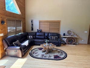 Ein gemütliches Wohnzimmer mit einer Eckcouch, einem runden Couchtisch und Holzboden.