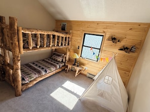Ein gemütliches Zimmer mit einem Etagenbett, einem kleinen Tisch, einem Fenster und einem Zelt.