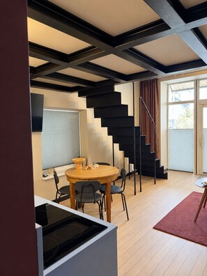Un intérieur moderne comprenant un escalier, un coin repas et une cuisine.