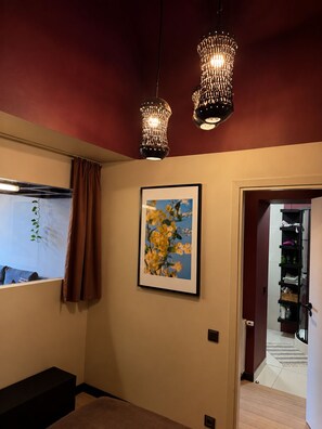 A room with a window, a framed picture, a bench, and a door leading to another room. - G Loft – Spacious Apartment with Bathtub & Private Entrance (Kaunas)