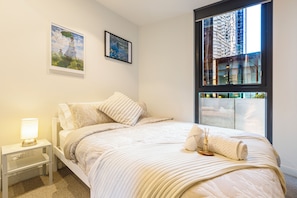 Un dormitorio con cama, una mesita de noche, una lámpara y dos cuadros en la pared.