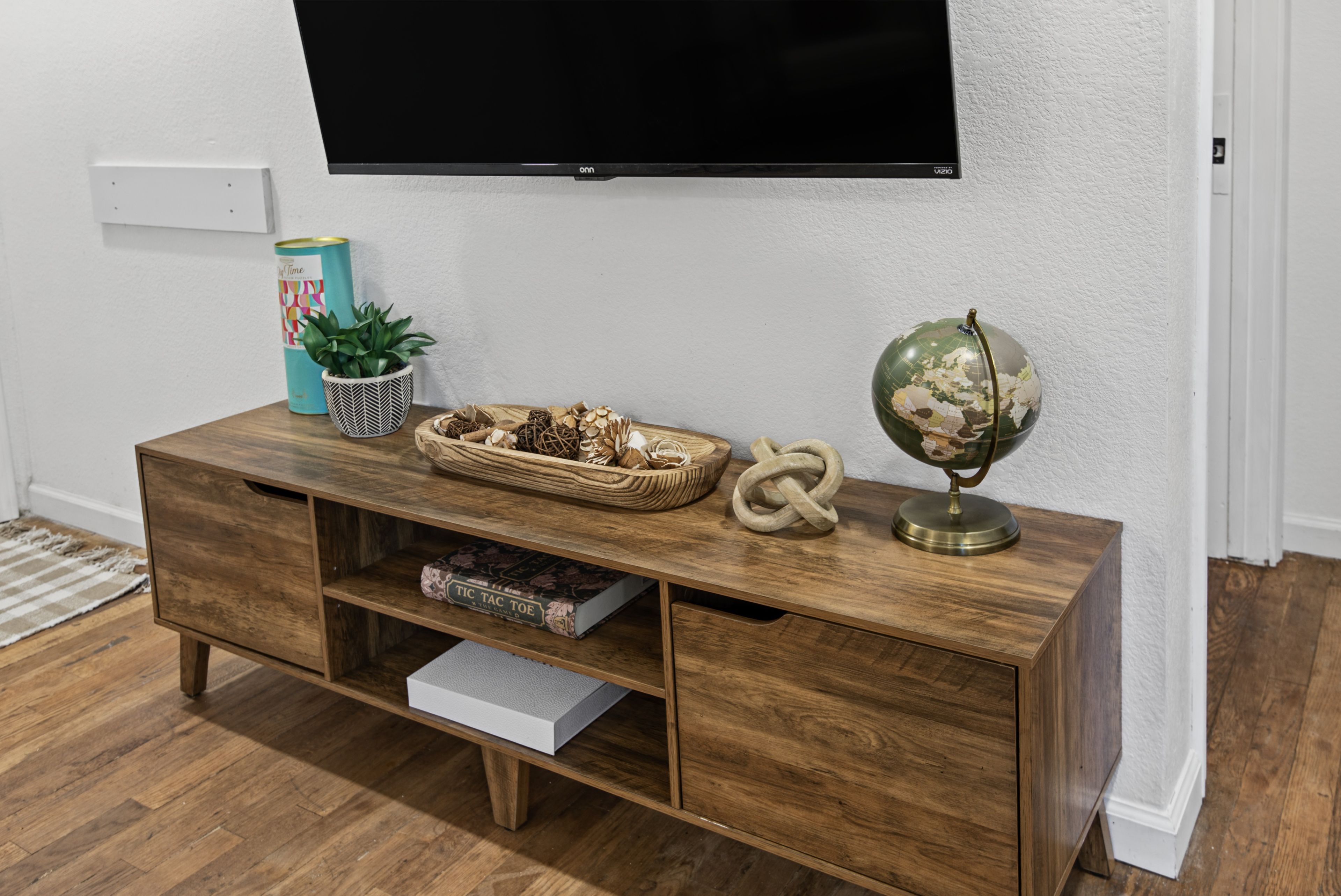 Un meuble de rangement pour appareils multimédias en bois, avec un téléviseur à écran plat fixé au-dessus.