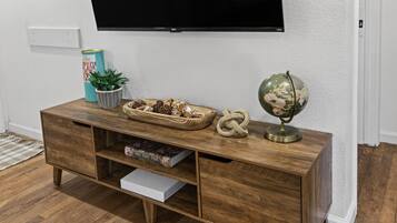 Un meuble de rangement pour appareils multimédias en bois, avec un téléviseur à écran plat fixé au-dessus.