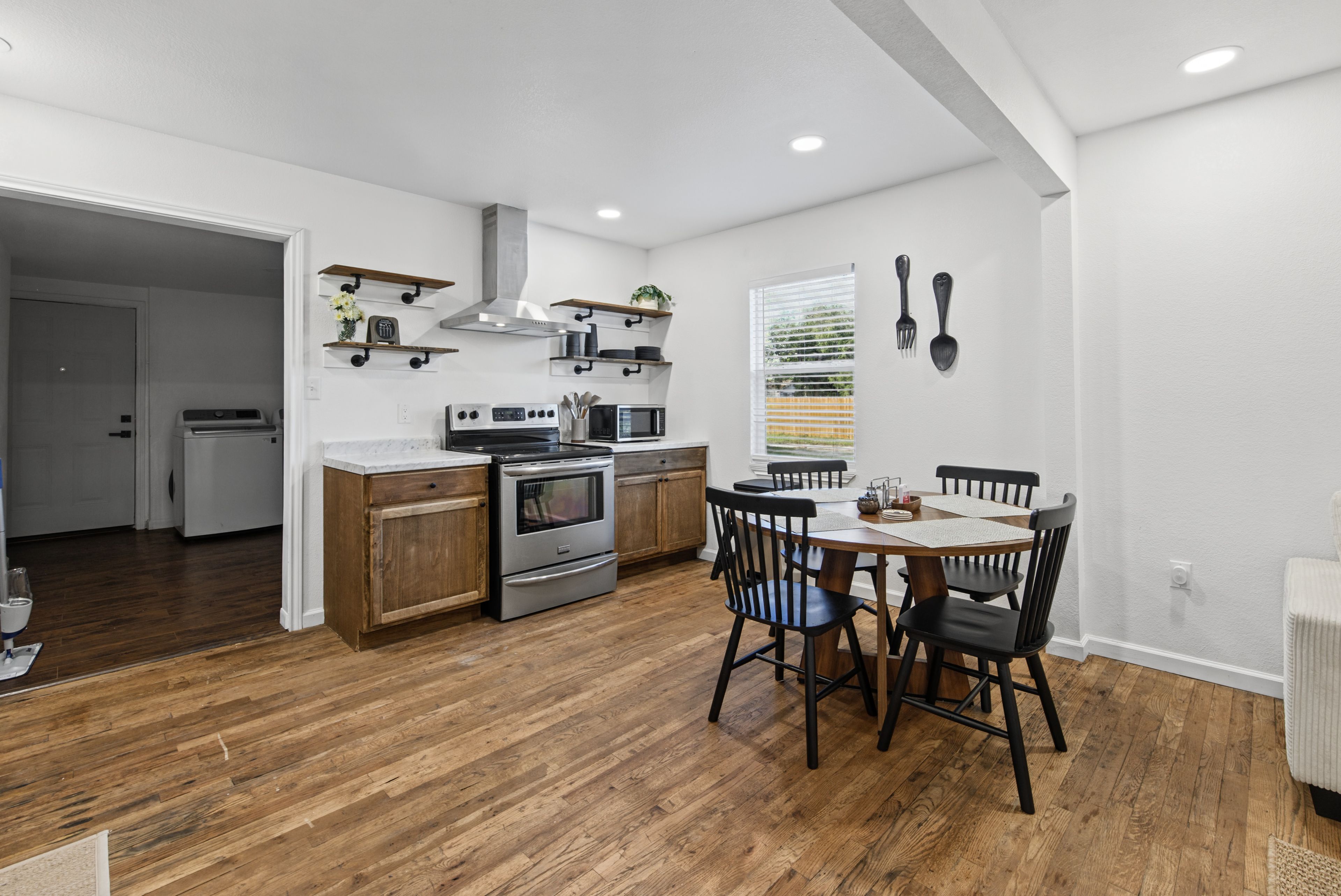 Une cuisine moderne avec des meubles en bois, un four encastré et un coin repas comprenant une table et des chaises.