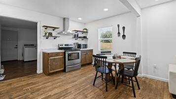 Une cuisine moderne avec des meubles en bois, un four encastré et un coin repas comprenant une table et des chaises.