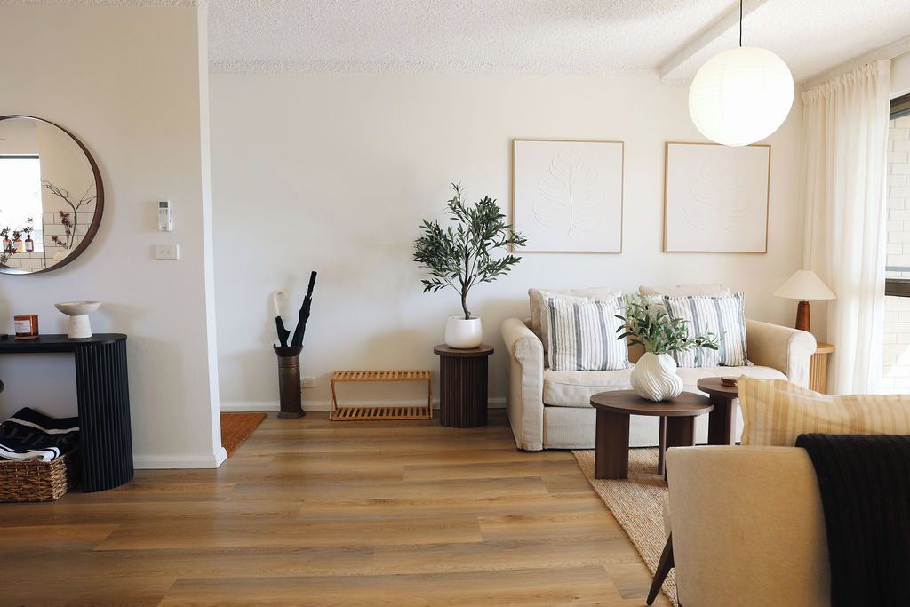 Un salon comprenant un canapé, une table basse, une table d’appoint, un lampadaire et une plante.