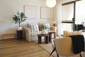 A living room with a sofa, two side tables, a potted plant, and a chair. - Stylish Coastal Retreat | 250m to Lighthouse Beach (East Ballina)