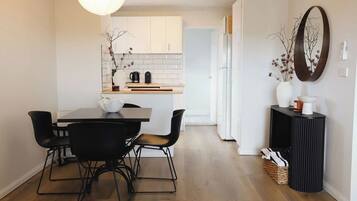 Une cuisine moderne avec des meubles blancs, un plan de travail en bois et un coin repas comprenant une table et des chaises.