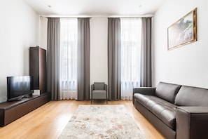 Una sala de estar moderna con un televisor de pantalla plana, un sofá, un sillón y una alfombra.