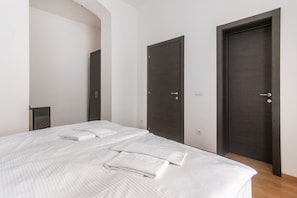 A hotel room with a bed, two doors, and a small table. - 2 Bedroom Apartment Sleeps 4 - Free Parking (Praha 2)