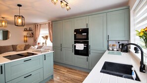 A modern kitchen with light blue cabinets, a black refrigerator, and a white countertop. - 2-Bed House Sleeps 4 with Parking & Garden (Skegness)