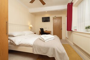 A bedroom with a bed, a desk, a chair, a television, and a window with curtains. - 11 Bedroom Cottage with Hot Tub and Parking (Derby)