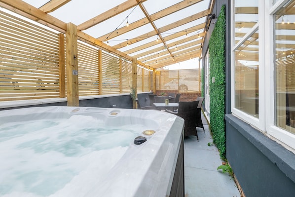 A hot tub area with wooden beams, a glass wall, and a green wall with plants. - 11 Bedroom Cottage with Hot Tub and Parking (Derby)
