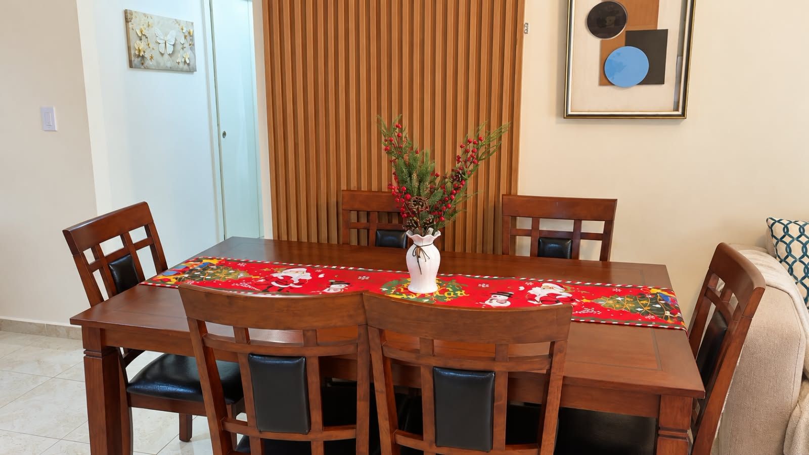 A dining area with a wooden table, chairs, and a vase with flowers.