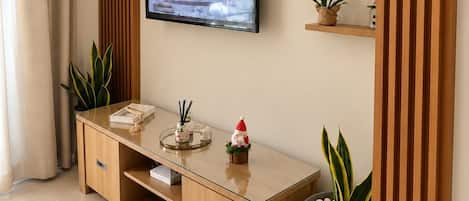 A modern living room with a TV mounted on a wooden wall, a wooden console table, and potted plants.