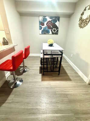 A dining area with a white table, four red chairs, and a vase of yellow flowers. - 2-bedroom apartment in beautiful Houston with AC and fitness room (Houston)
