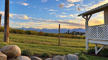 A rural landscape with a wooden fence, a white lattice structure, and a clear sky.